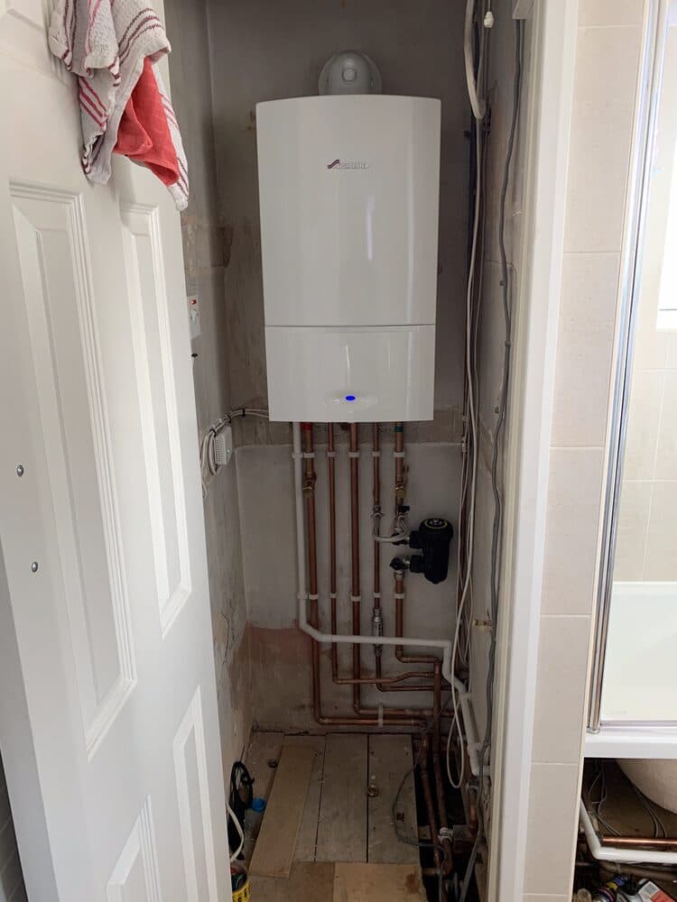 Newly fitted boiler in an airing cupboard with fresh pipework