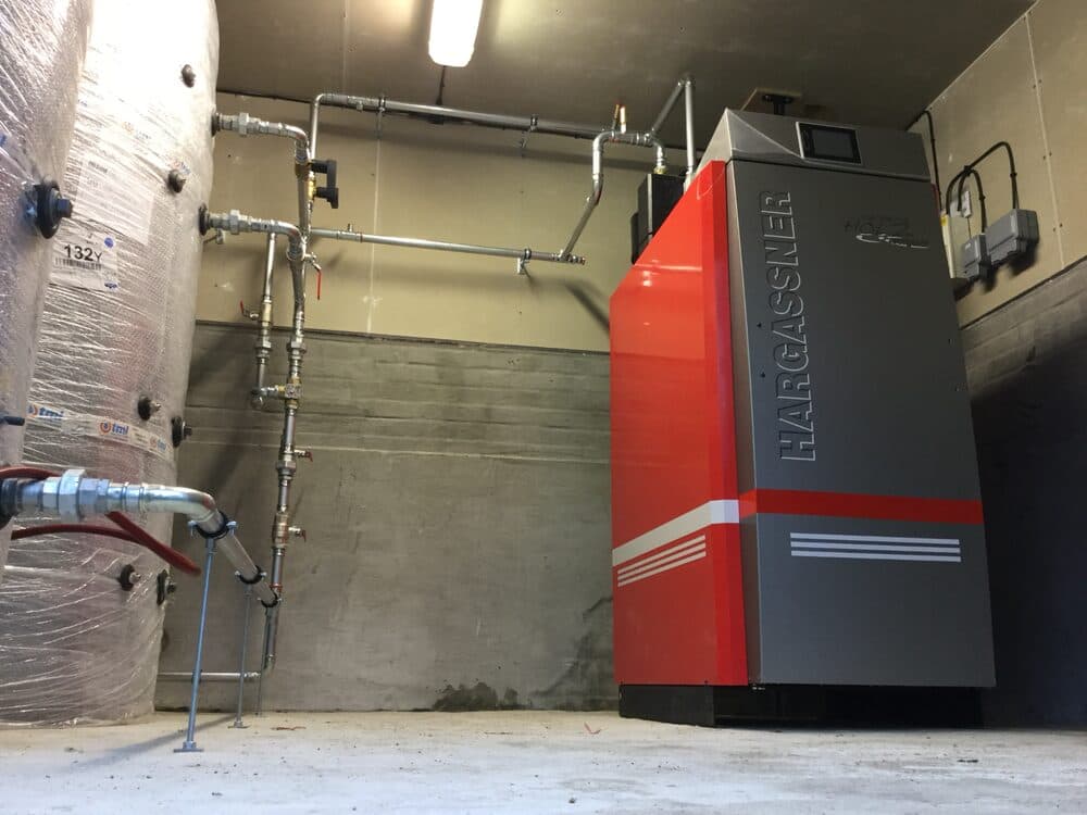 Hargassner biomass boiler installed alongside a hot water cylinder